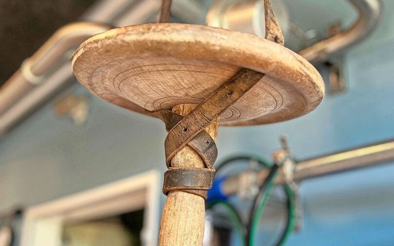 Ein holziger, altmodischer Melkschemel hängt von der Decke.
