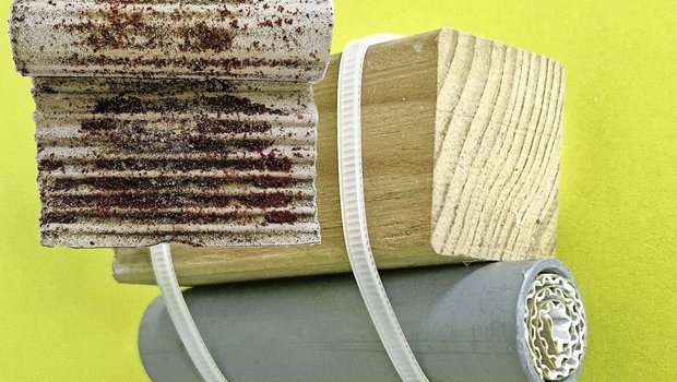 Milbenfalle aus Kunststoffrohr und aufgerolltem Wellkarton, unter einer Sitzstange befestigt. Zur Kontrolle wird das Papier herausgestossen und entrollt