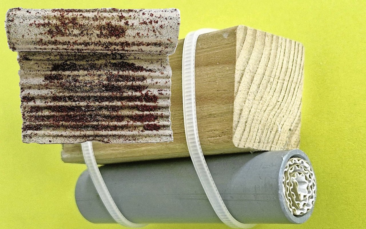 Milbenfalle aus Kunststoffrohr und aufgerolltem Wellkarton, unter einer Sitzstange befestigt. Zur Kontrolle wird das Papier herausgestossen und entrollt