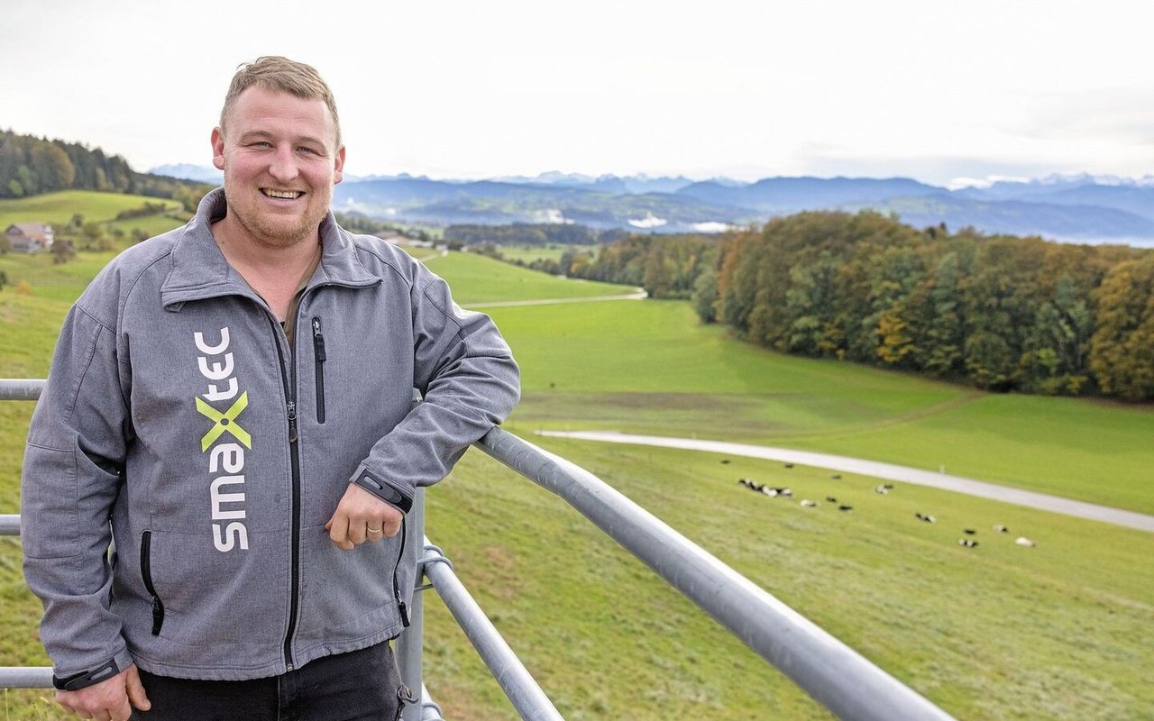 Tobias Wehnert lehnt sich an die Metallstangen im Laufhof. Hinter ihm ist die Kuhweide zu sehen.